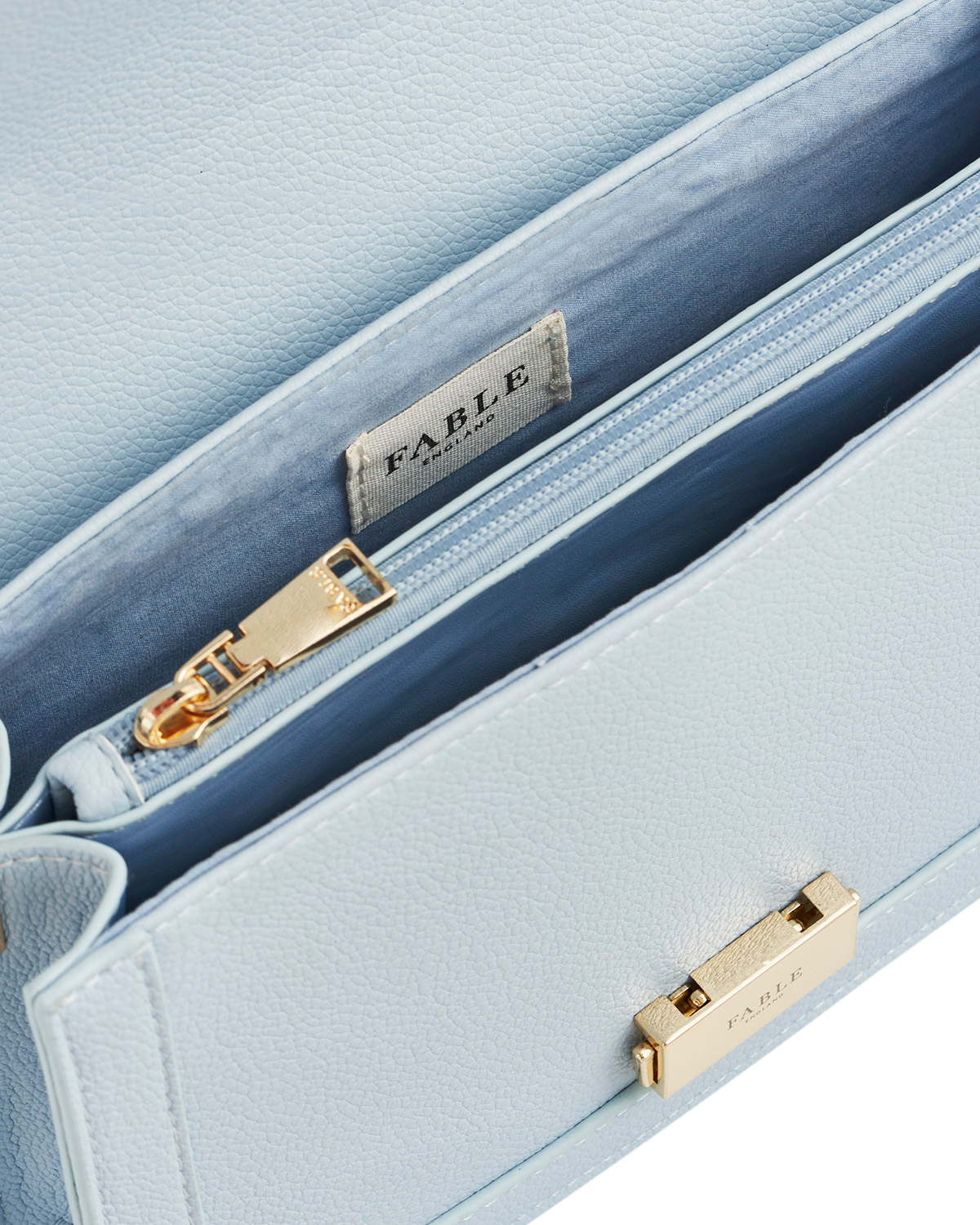 Light blue handbag with gold zippers and 'Fable' brand label.