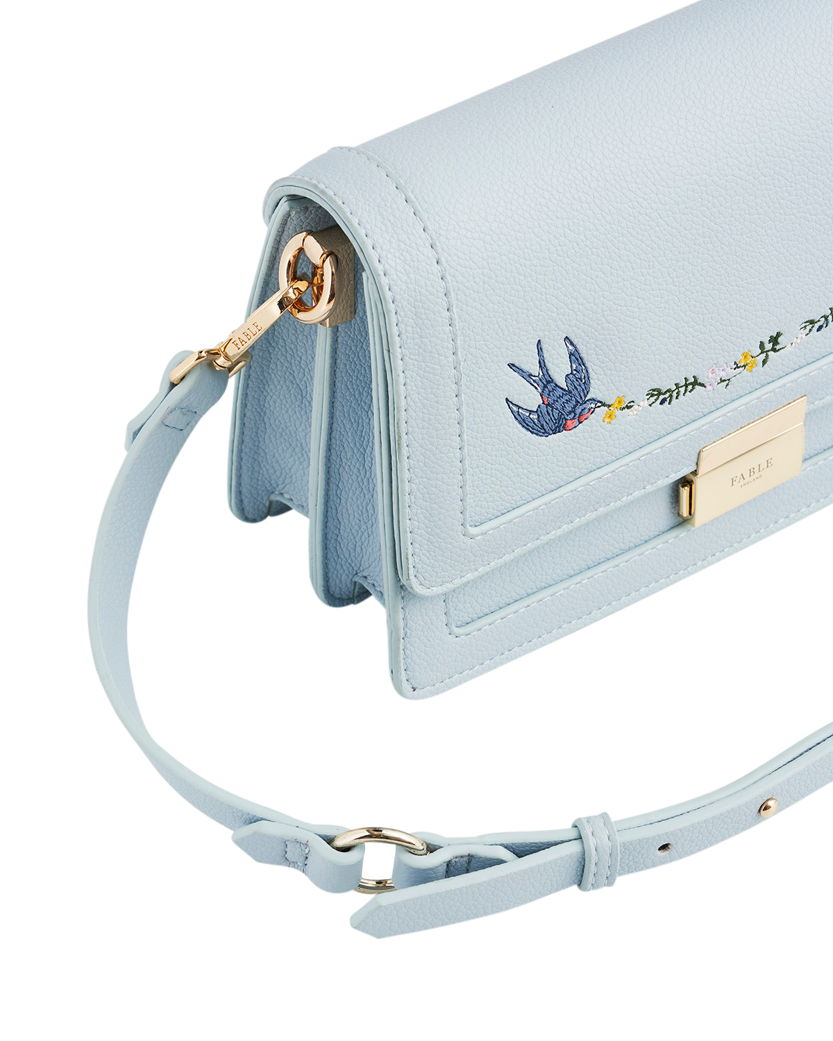Light blue handbag with embroidered design on a white background