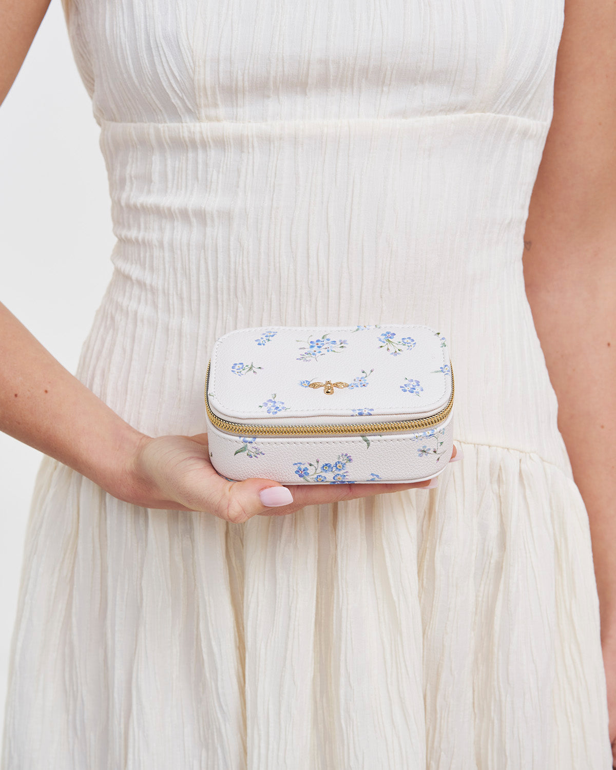 Person holding a small floral-patterned jewelry box against a white background