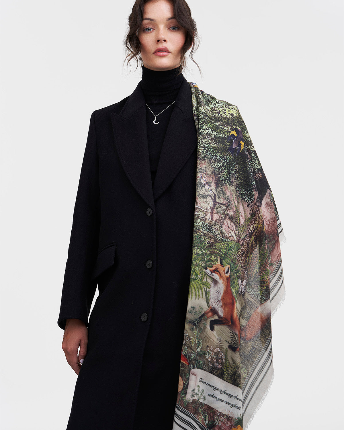 Woman wearing a black coat with a patterned scarf featuring animals on a white background