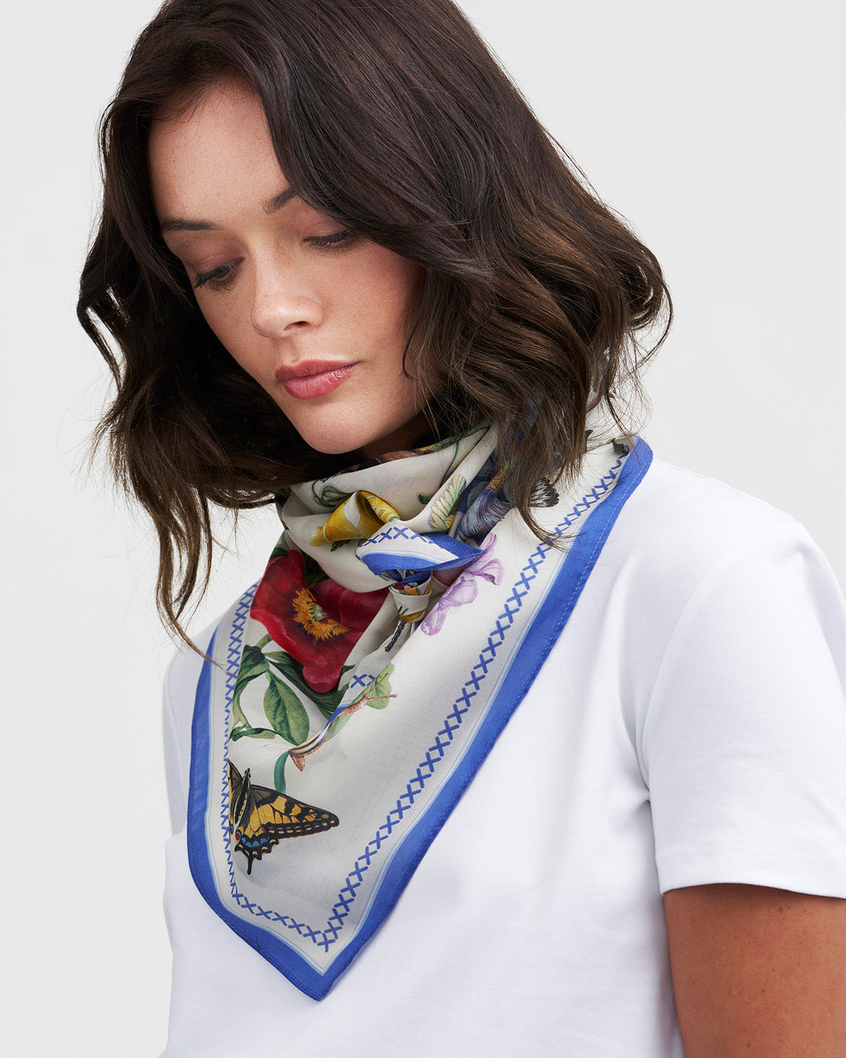 Woman wearing a floral scarf with butterfly design on a white background