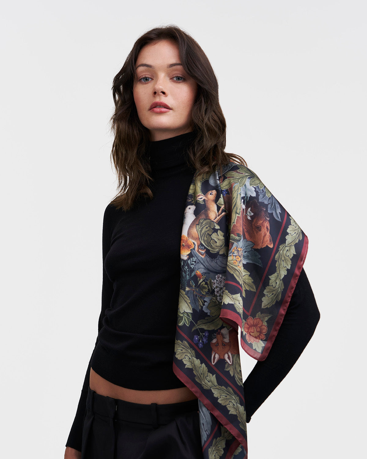 Woman wearing a black turtleneck and patterned scarf on a white background
