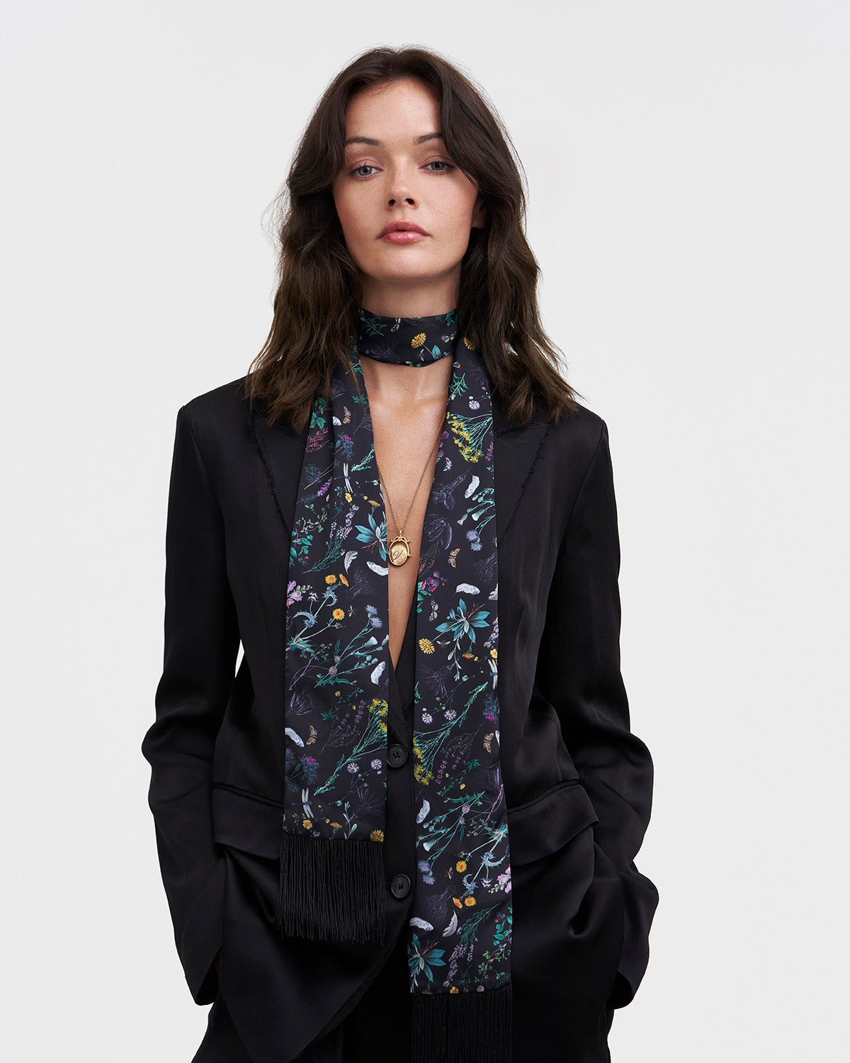 Woman wearing a black floral scarf with a plain background