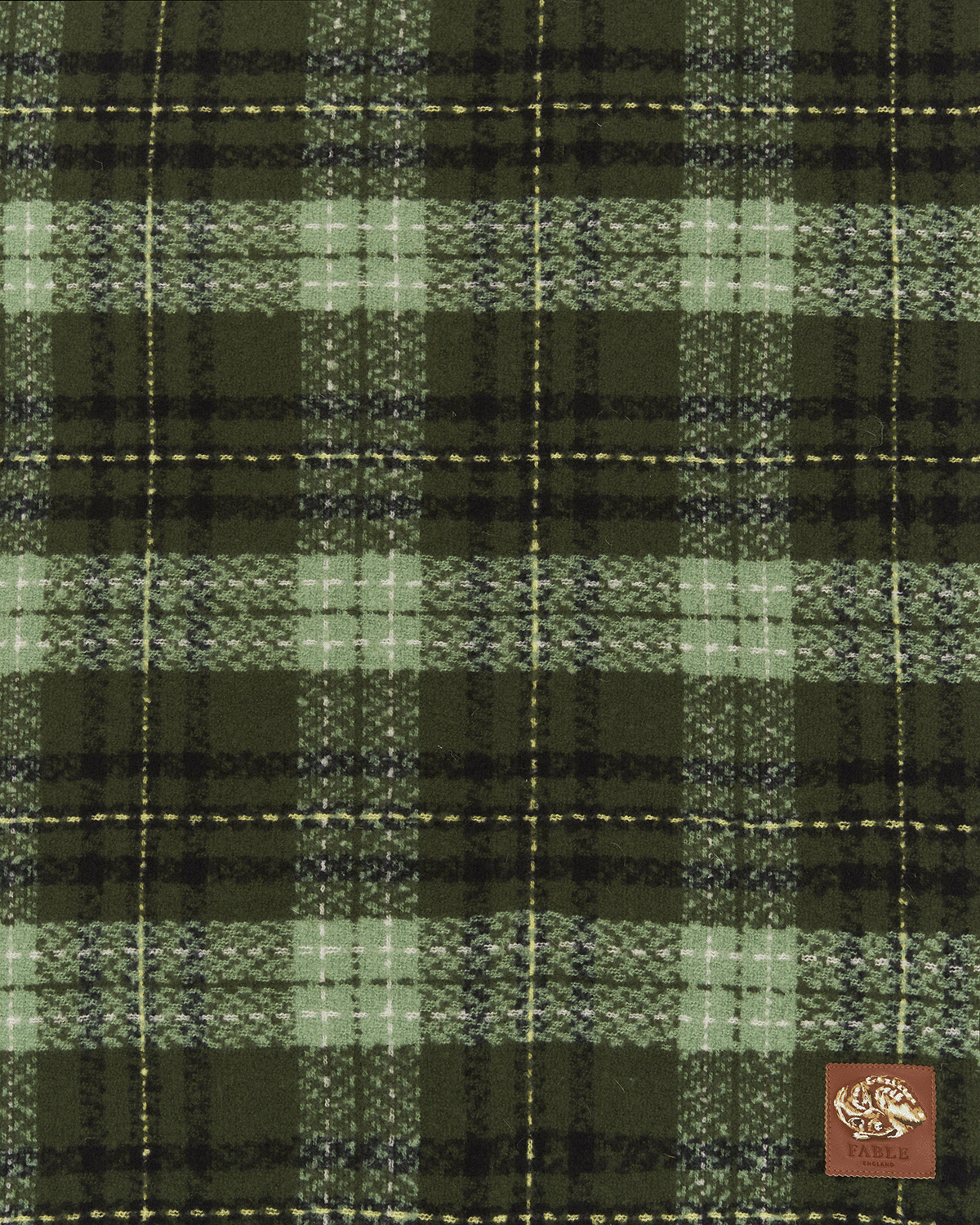 Green and black plaid fabric with a brand logo in the corner