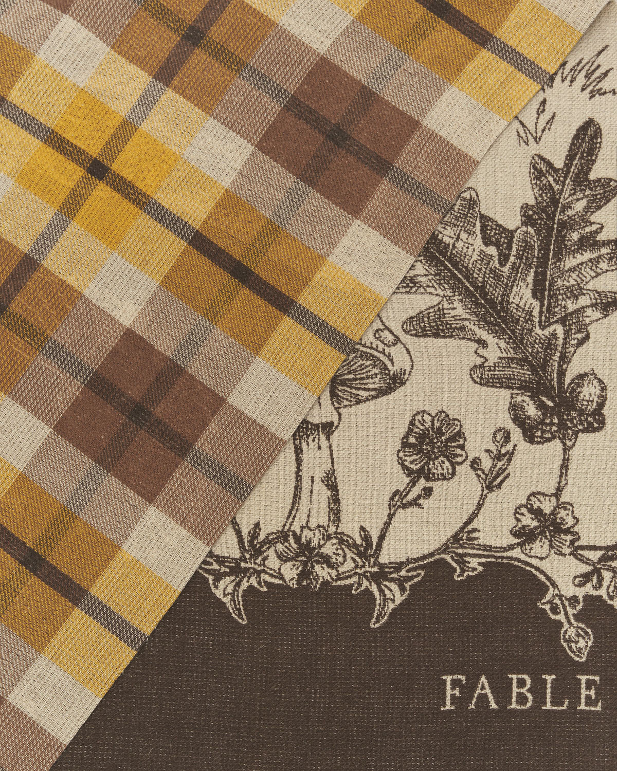 Fabric with plaid pattern and nature-themed design, featuring the brand 'Fable'.
