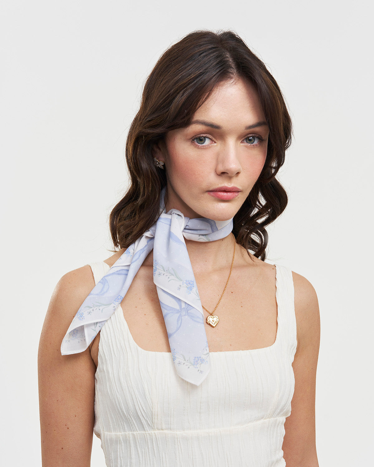 Model wearing blue scarf around neck wearing a white dress