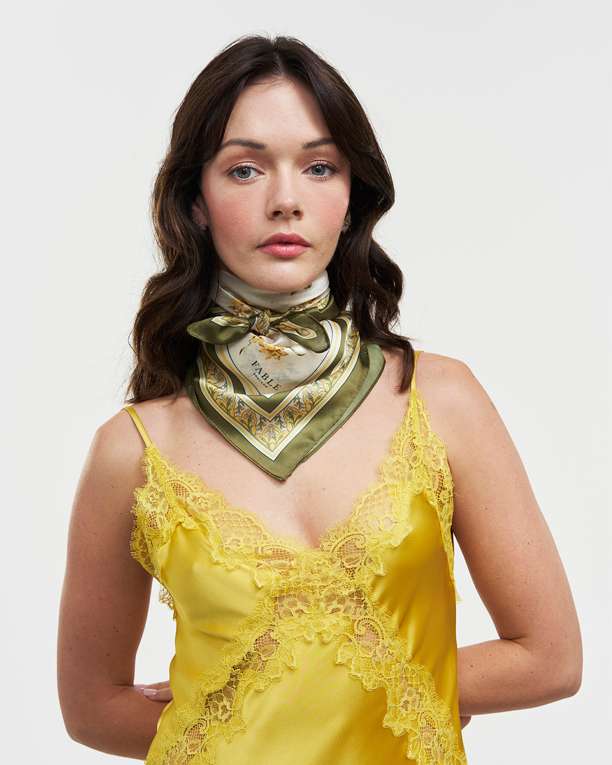 Woman wearing green and yellow silky scarf around neck with white background