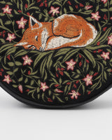 Close up detail of embroidered sleepy fox motif on navy circle crossbody bag.