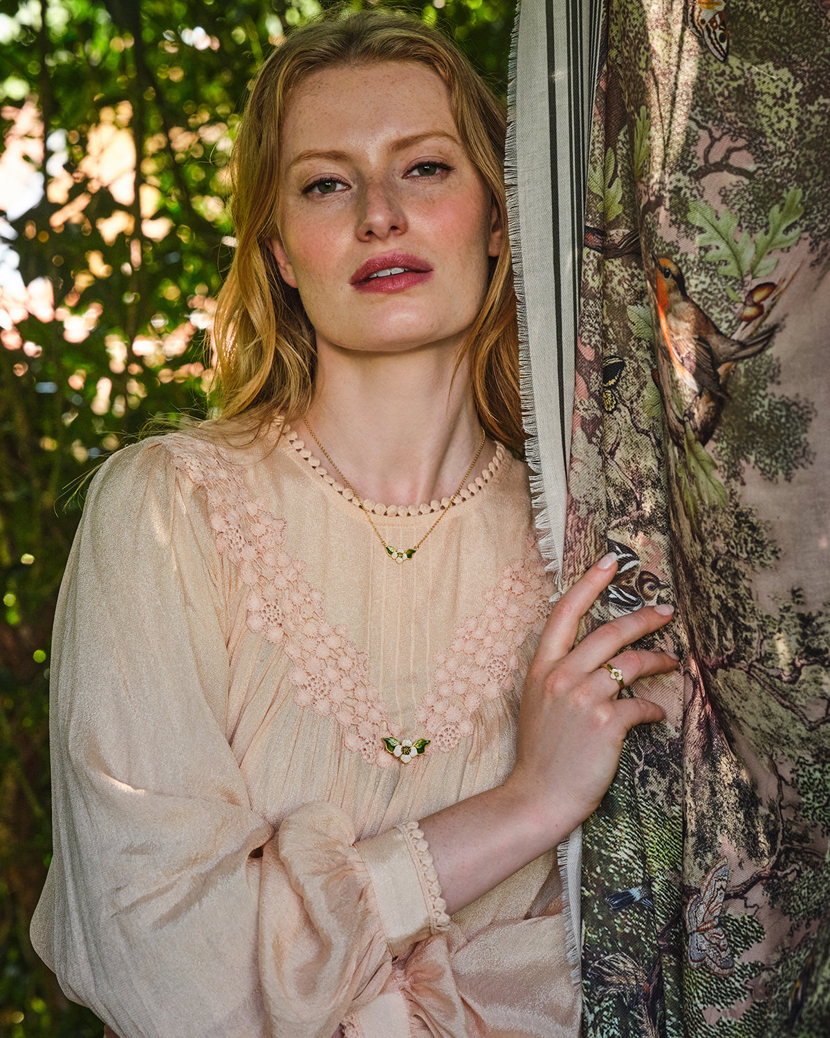 Woman in a light-colored dress holding a woodland print scarf with nature-themed design.