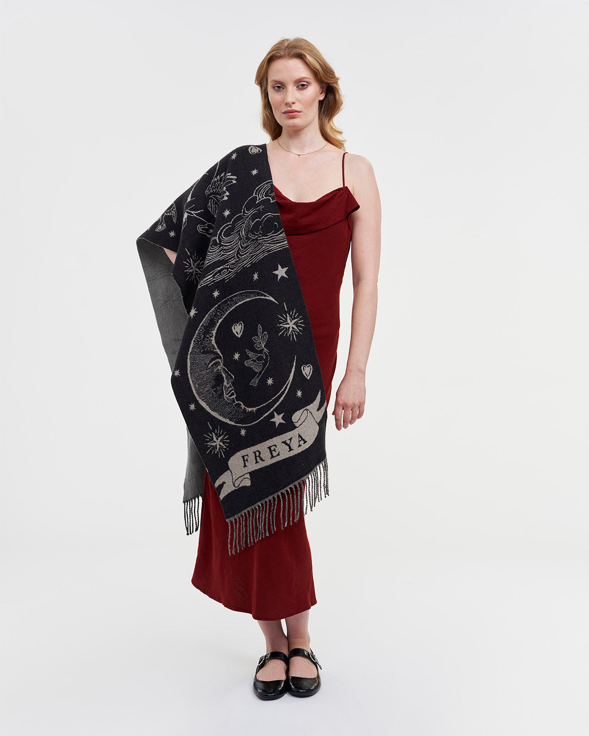 Woman wearing a dark scarf with celestial designs and a red dress on a white background