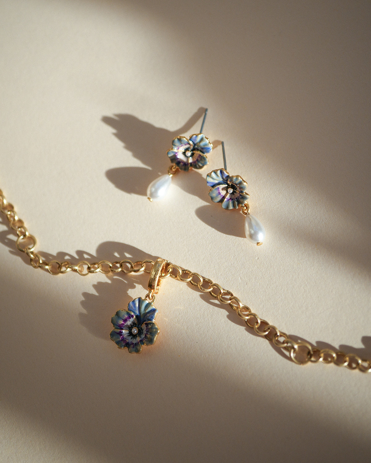 Gold necklace with floral pendants on a beige background