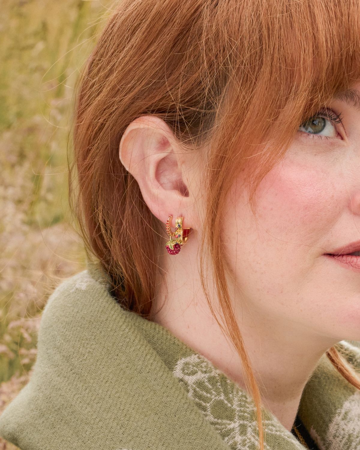 Model wearing Orla Raspberry Huggie Earrings and Orla Hedgerow Heart Hoop Earrings in Gold