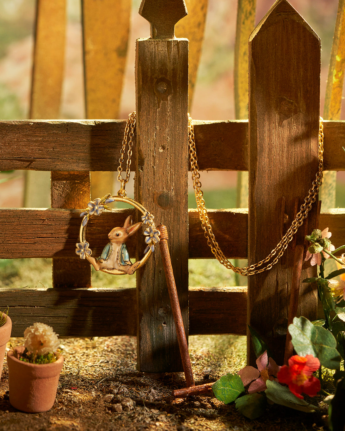 Decorative wreath with a rabbit design hanging on a wooden fence with flowers and plants around.
