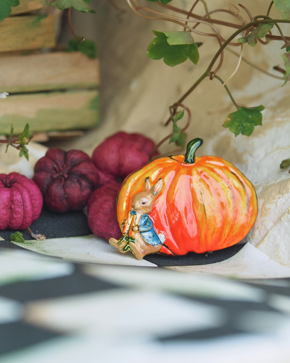 enamel pumpkin brooch with a rabbit rabbit with other pumpkins in the background.