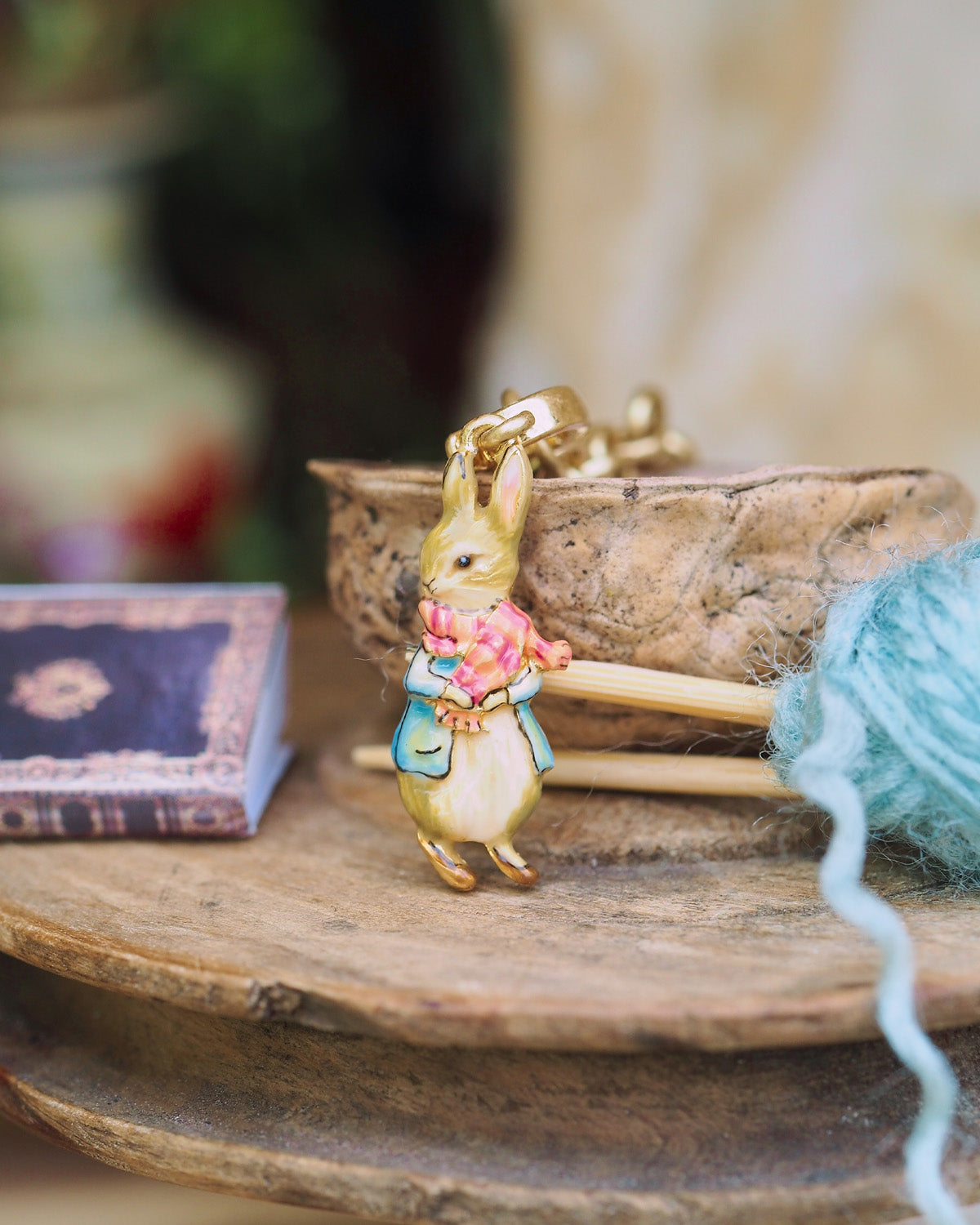 Peter Rabbit wearing red scarf charm on a wooden surface