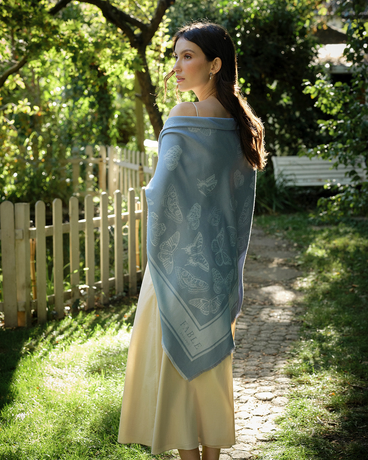 Woman wearing a blue patterned shawl in a garden setting
