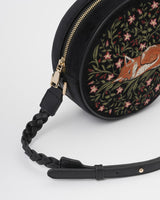 Close up detail of plaited crossbody strap of bag. Showing detail of the brass zip.