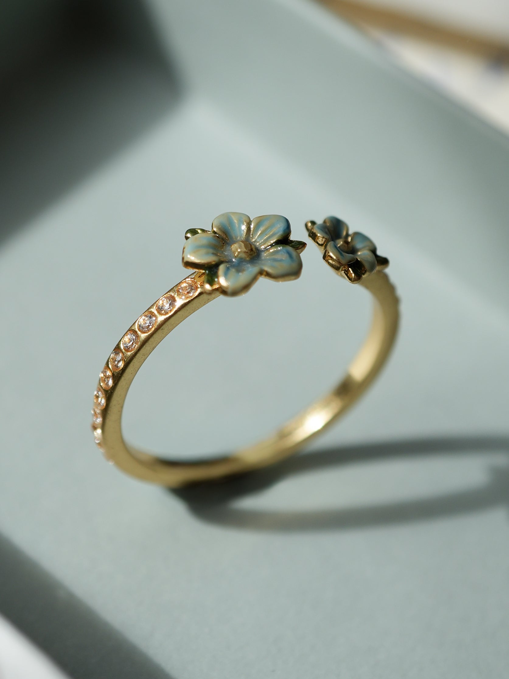 Gold ring with floral designs on a light gray background