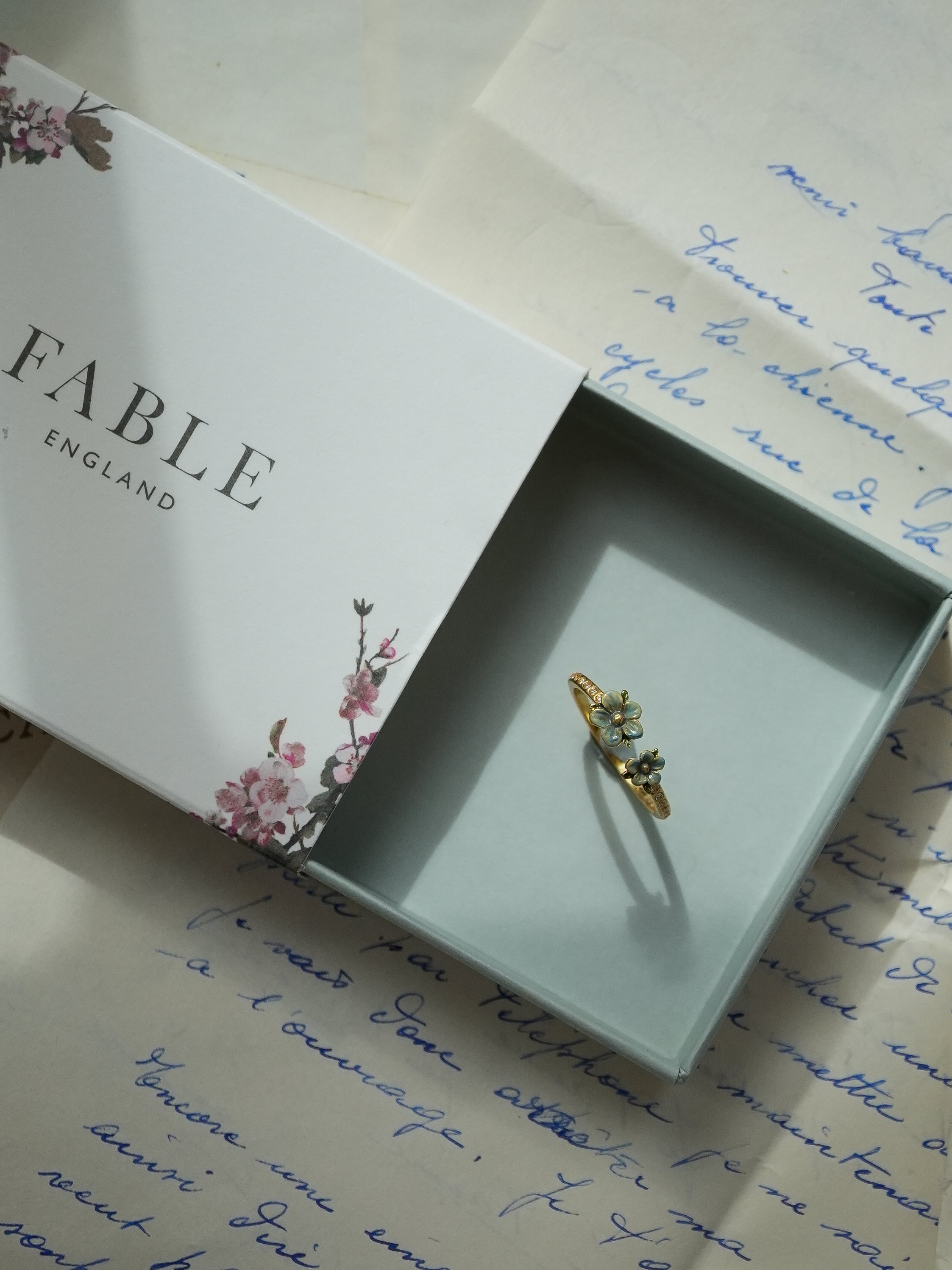 Gold ring in a box with 'Fable' branding on a handwritten letter background
