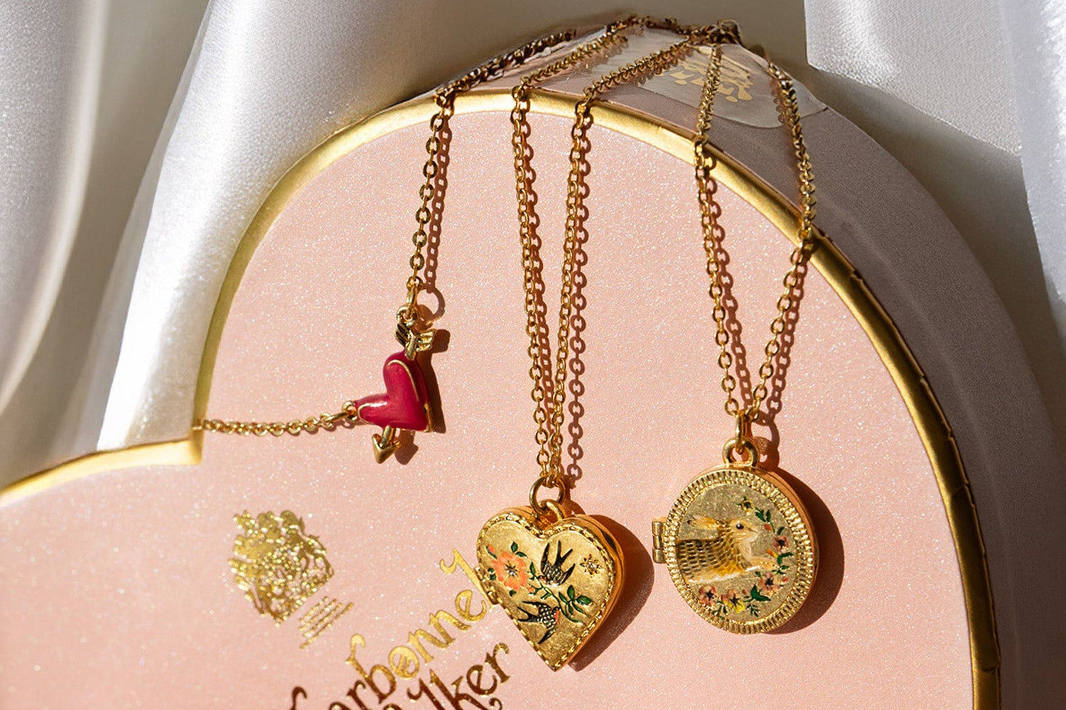 Gold necklaces with heart and coin designs on a Harrods branded box.