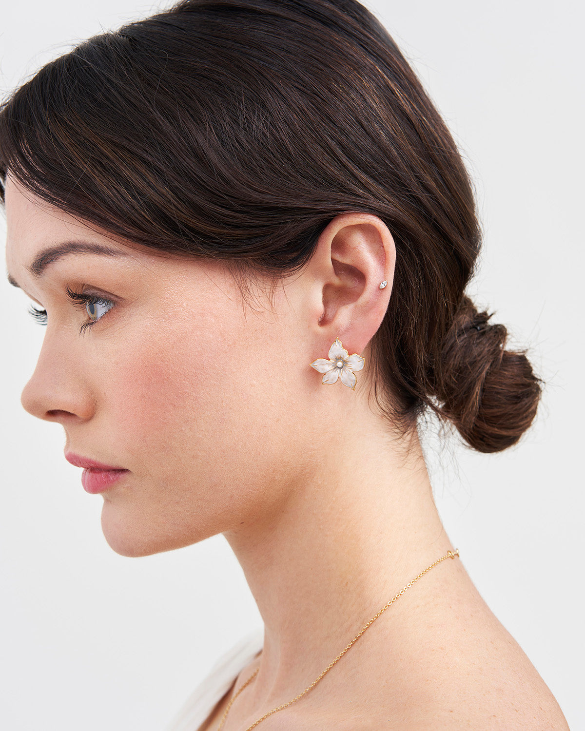 Woman wearing an oversized jasmine earring with a plain background