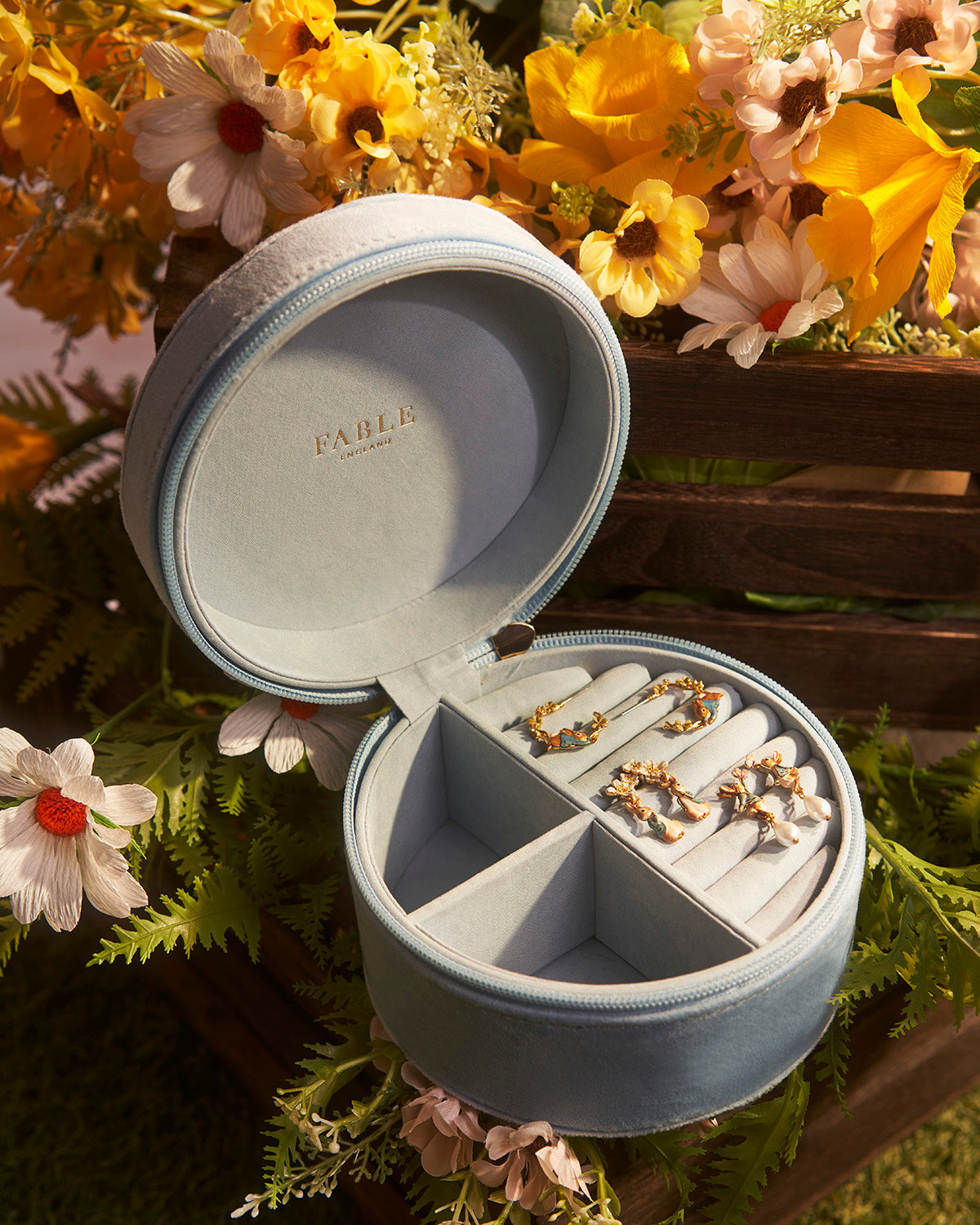 Open round jewellery box with necklaces on a floral background