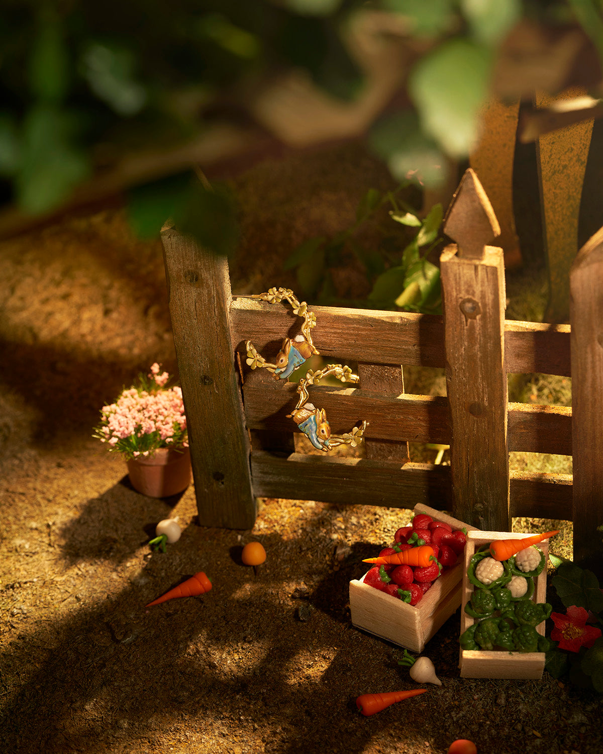 Miniature garden scene with wooden fence, plants, and small figures in a natural setting.