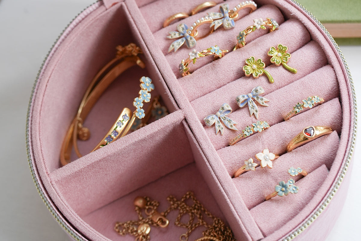 Pink jewelry box with rings and bracelets on a light surface
