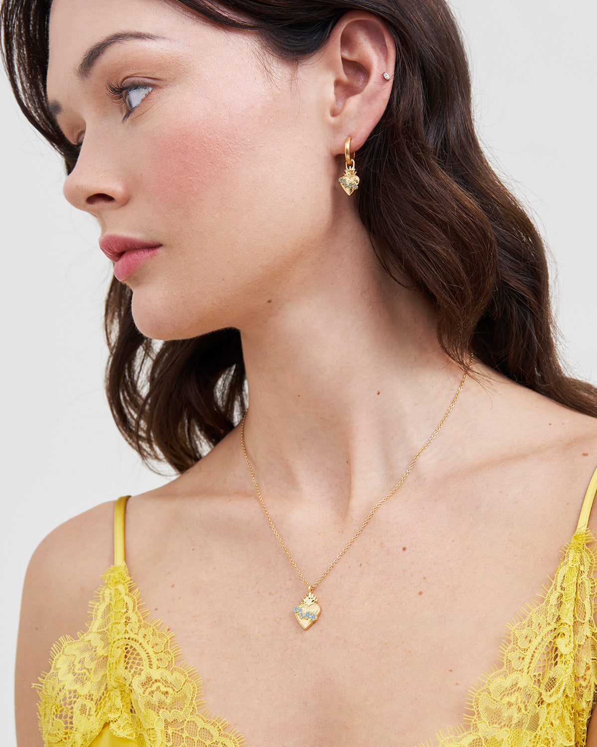 Woman wearing Gold Sacred Heart Necklace against a white background