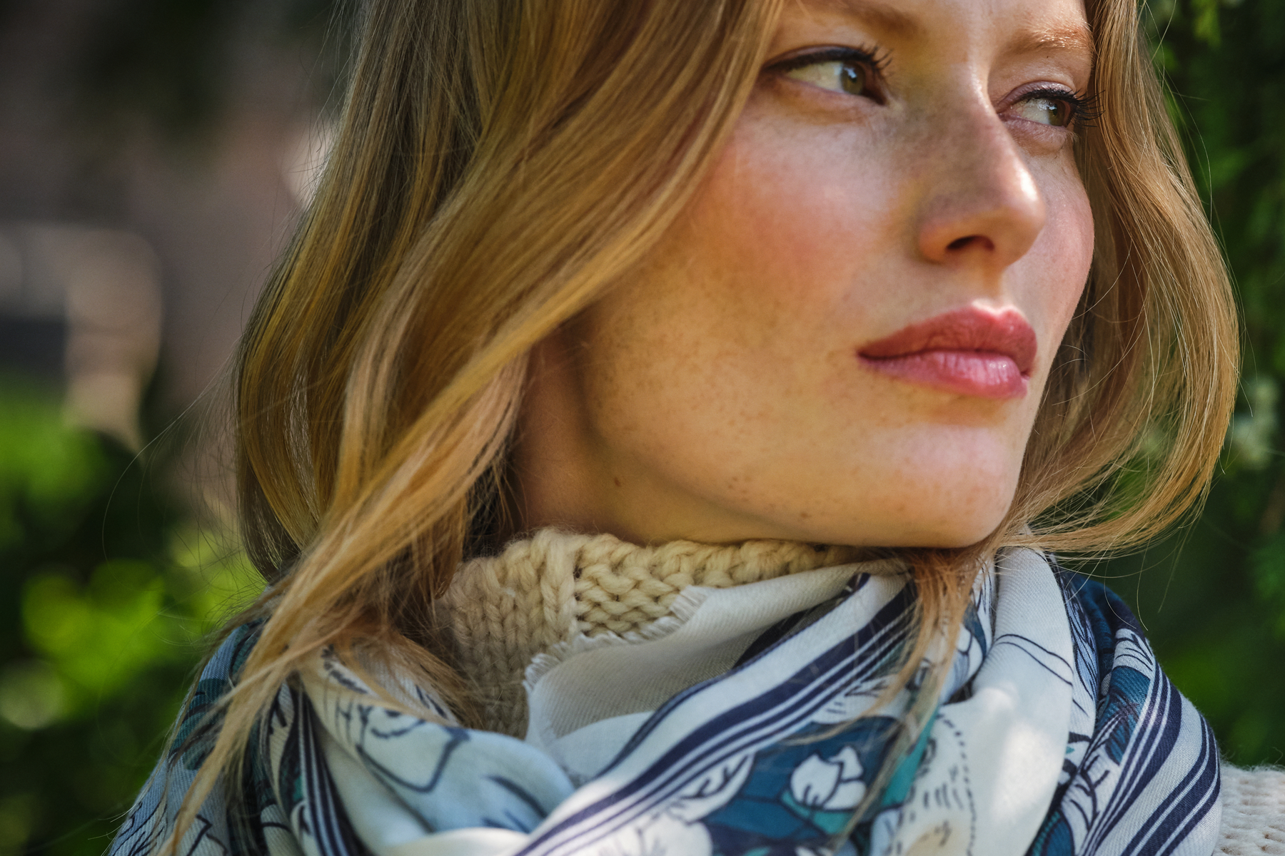 Woman wearing a floral scarf with a blurred green background